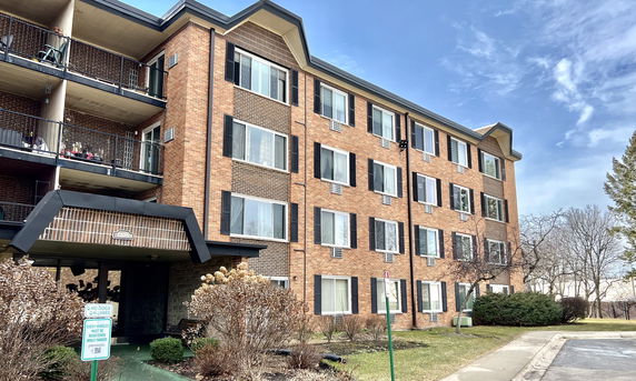 Front view of a multi-story brick apartment building with balconies.