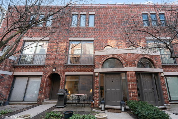 Front view of a multi-story brick townhouse with large windows and arched doorways.