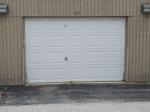 Front view of a building with a white garage door and vertical wood paneling.