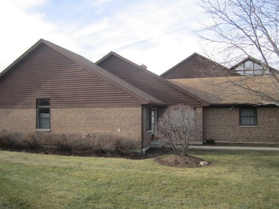 Front view of a single-story house with a brick facade and gabled roof.