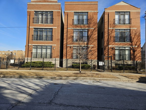 Front view of three adjacent multi-story brick apartment buildings.