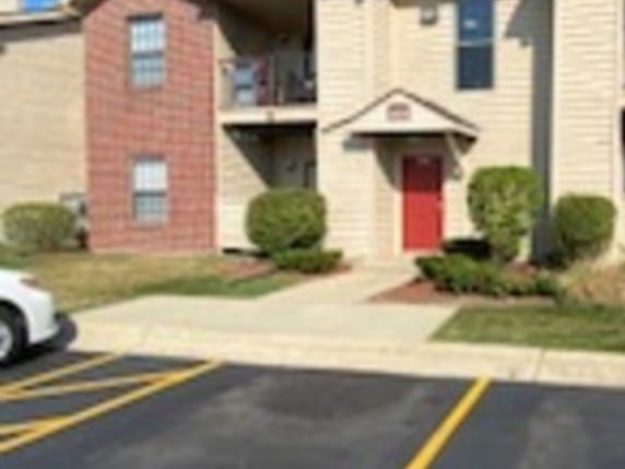 Front view of a multi-story apartment building with a red door.