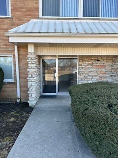 Front view of a building entrance with glass doors and brick exterior.