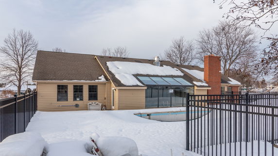 Front view of a single-story house with snow-covered roof and a glass extension.