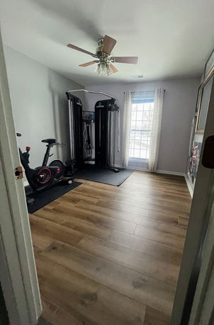 Home gym room with exercise equipment and ceiling fan.