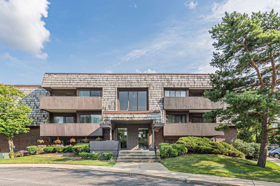 Front view of a multi-story building with balconies and a shingled roof.