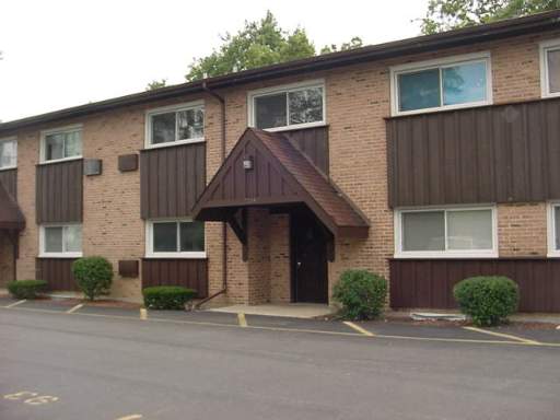 Front view of a multi-story brick building with brown accents and a covered entrance.
