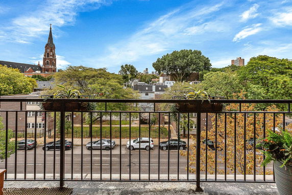 View from a balcony showing a church spire, trees, and buildings in the distance.