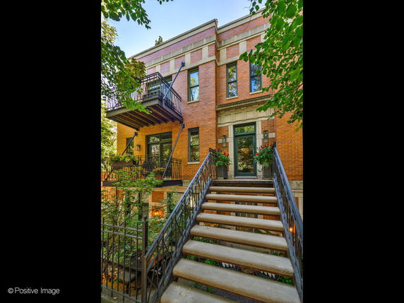 Front view of a multi-story brick building with a staircase leading to the entrance.