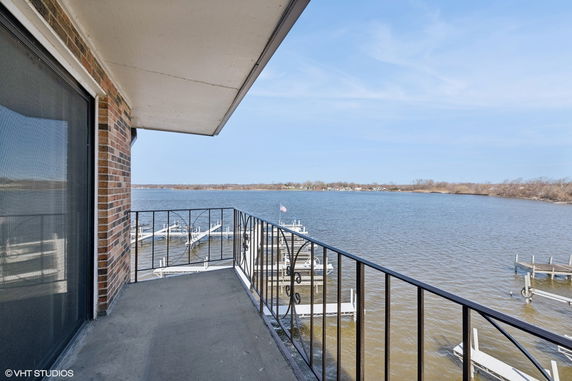 Balcony view of a lake with docks and distant shoreline.