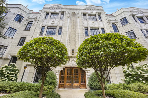 Front view of a multi-story building with ornate stone facade and large wooden doors.