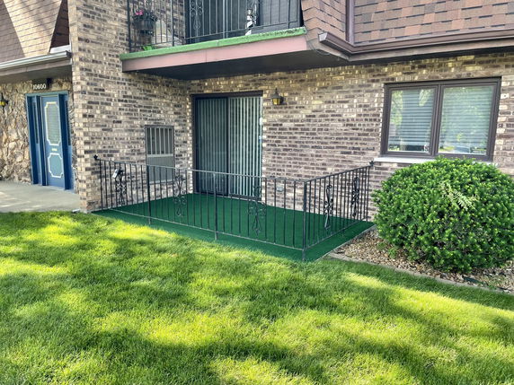 Front view of a two-story building with a fenced porch and brick exterior.