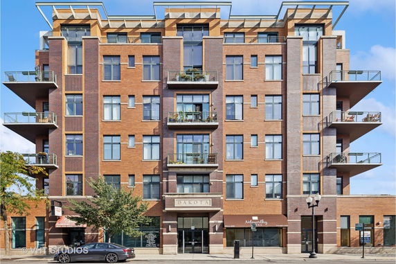 Front view of a multi-story brick apartment building with balconies.