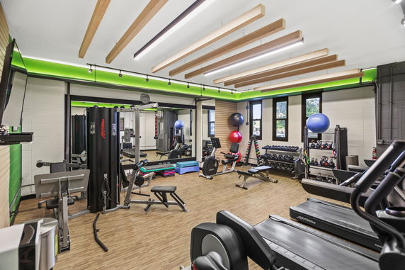 Indoor gym with various exercise equipment including treadmills, weight machines, and free weights.