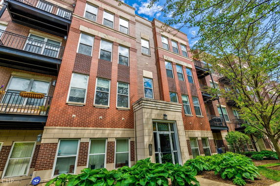 Front view of a multi-story brick apartment building with balconies.