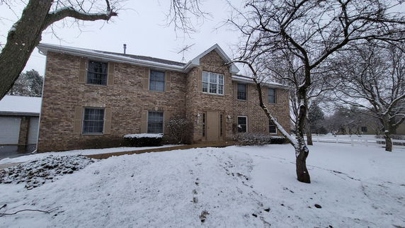 Front view of a two-story brick house with snow on the ground.