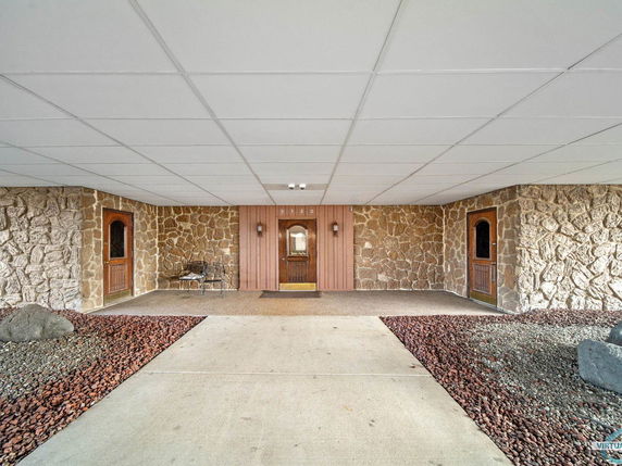 Front view of a building entrance with stone walls and two wooden doors.
