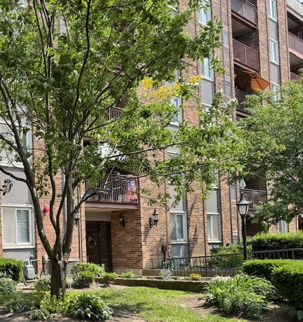Front view of a multi-story brick apartment building with balconies.