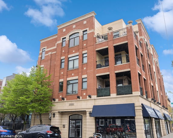 Front view of a multi-story brick building with large windows and balconies.