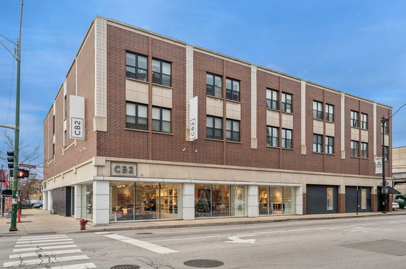 Front view of a three-story commercial building with large glass windows on the ground floor and brick facade.