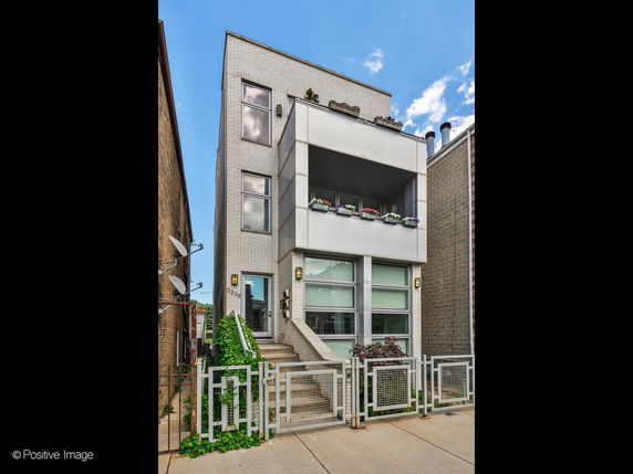 Front view of a modern multi-story building with a small balcony and metal fencing.