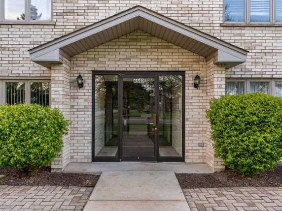 Front view of a building entrance with glass doors and brick exterior.