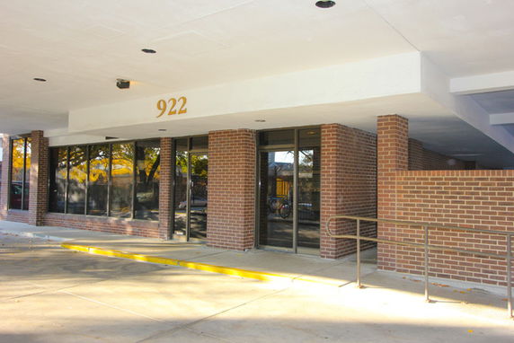 Front view of a brick-front building with large windows and a walkway.