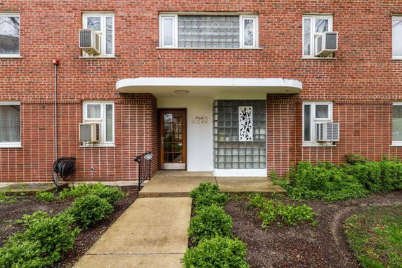 Front view of a brick apartment building with multiple windows and central entrance.