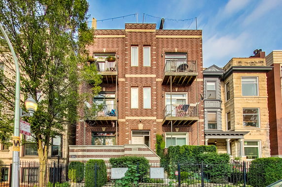 Front view of a multi-story brick residential building with balconies.