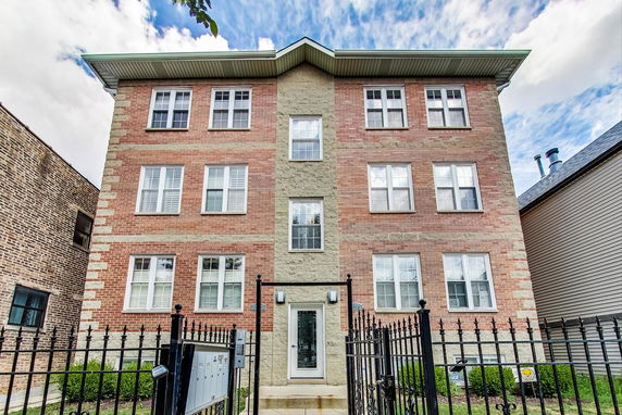 Front view of a three-story brick apartment building with multiple windows.