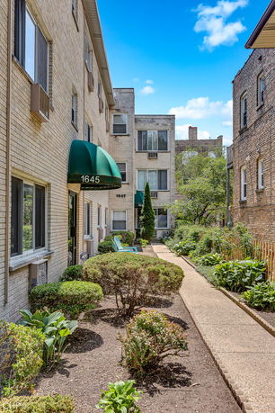 Front view of an apartment building with a walkway and garden.