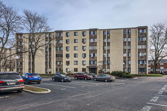 Front view of a multi-story apartment building with a parking area in front.