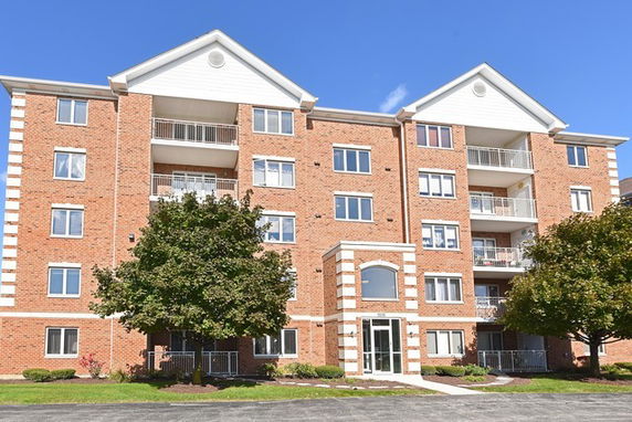 Front view of a multi-story brick apartment building with balconies.