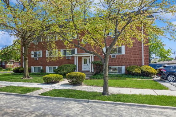 Front view of a brick apartment building with multiple windows and a central entrance.