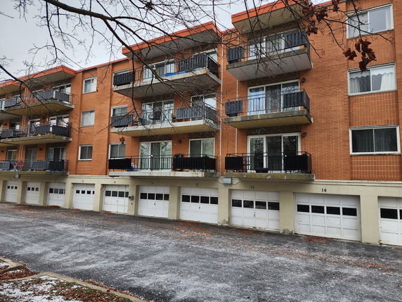 Front view of a multi-story apartment building with balconies and garages.