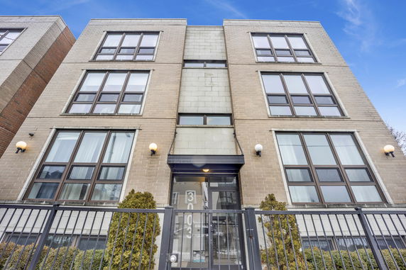 Front view of a multi-story building with large windows and a gated entrance.