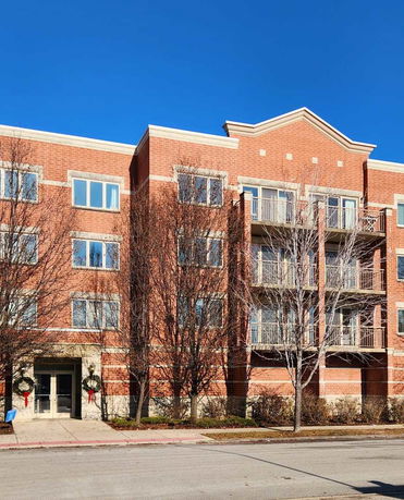 Front view of a multi-story brick apartment building with balconies.