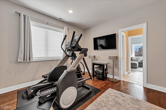 Home gym with exercise equipment and a mounted TV.
