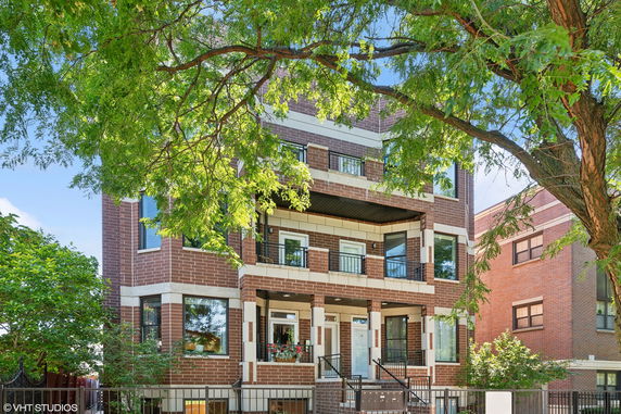 Front view of a three-story brick building with balconies.