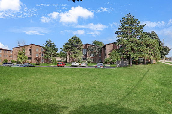 Front view of a multi-story apartment building with a parking area.