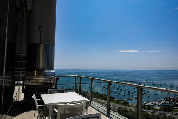 Panoramic view from a high-rise balcony overlooking a body of water with boats.