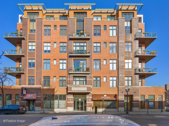 Front view of a multi-story residential building with balconies and large windows.