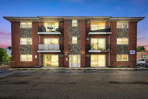 Front view of a multi-story brick apartment building with balconies.