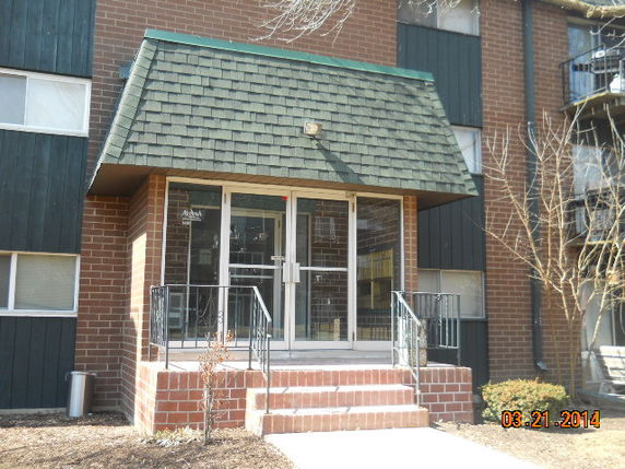 Front view of a building with a brick exterior and a green shingle-covered entrance.