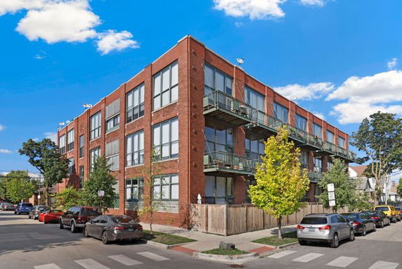 Front view of a multi-story brick apartment building with balconies.