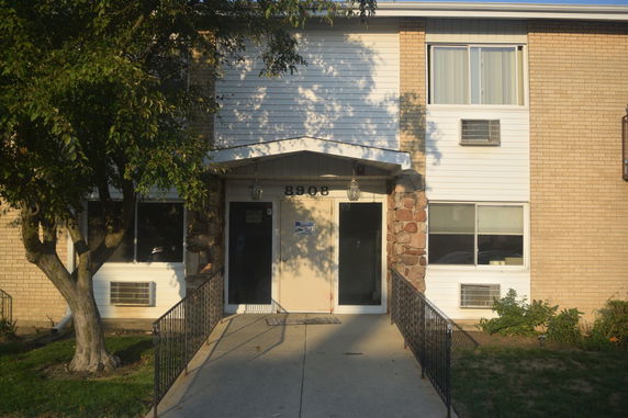 Front view of a multi-story building with brick and siding facade.