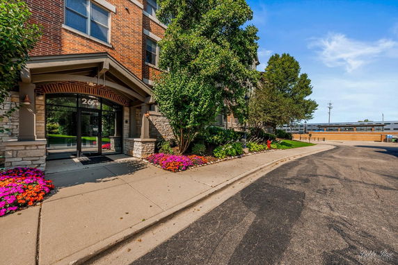 Front view of a brick building entrance with plants and flowers.