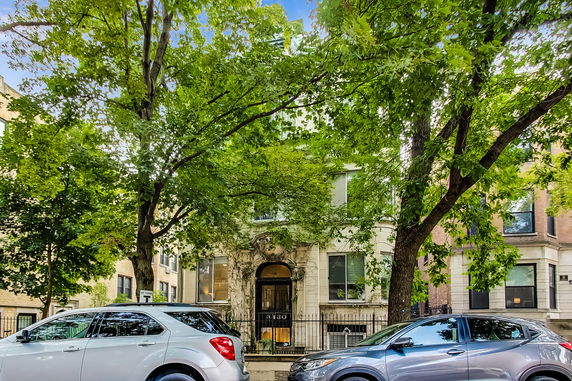Front view of a multi-story brick building with large windows and a decorative entrance.