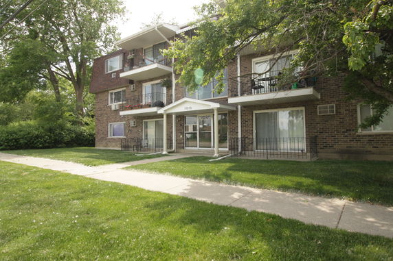 Front view of a three-story brick apartment building with balconies.