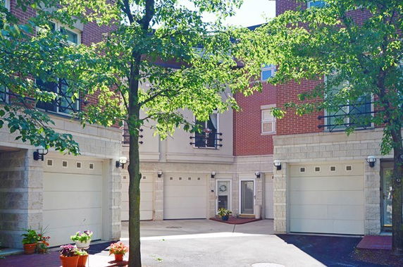 Outdoor parking area in front of townhouses with garage doors.
